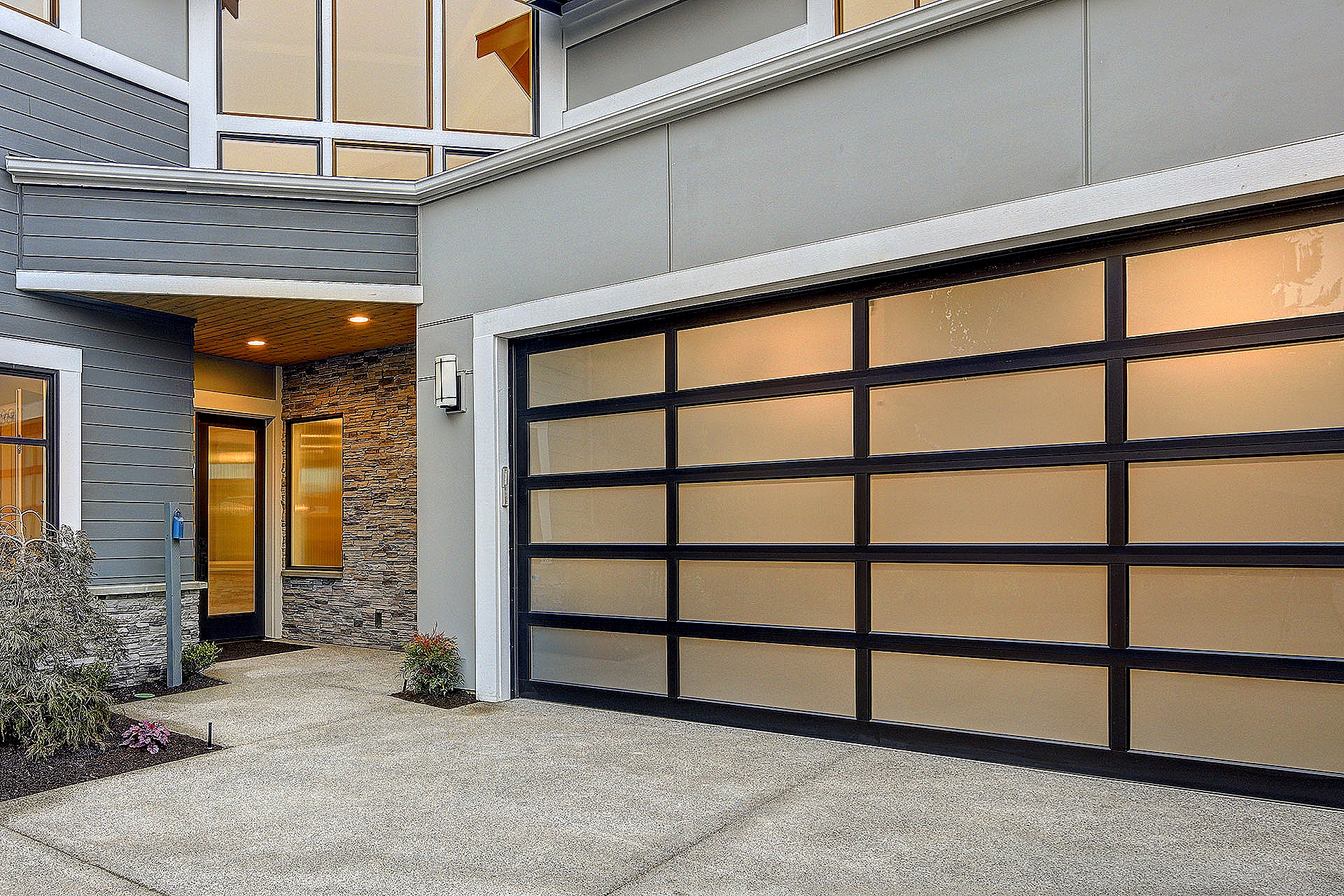 Modern house exterior with frosted glass garage door and stone accent wall.